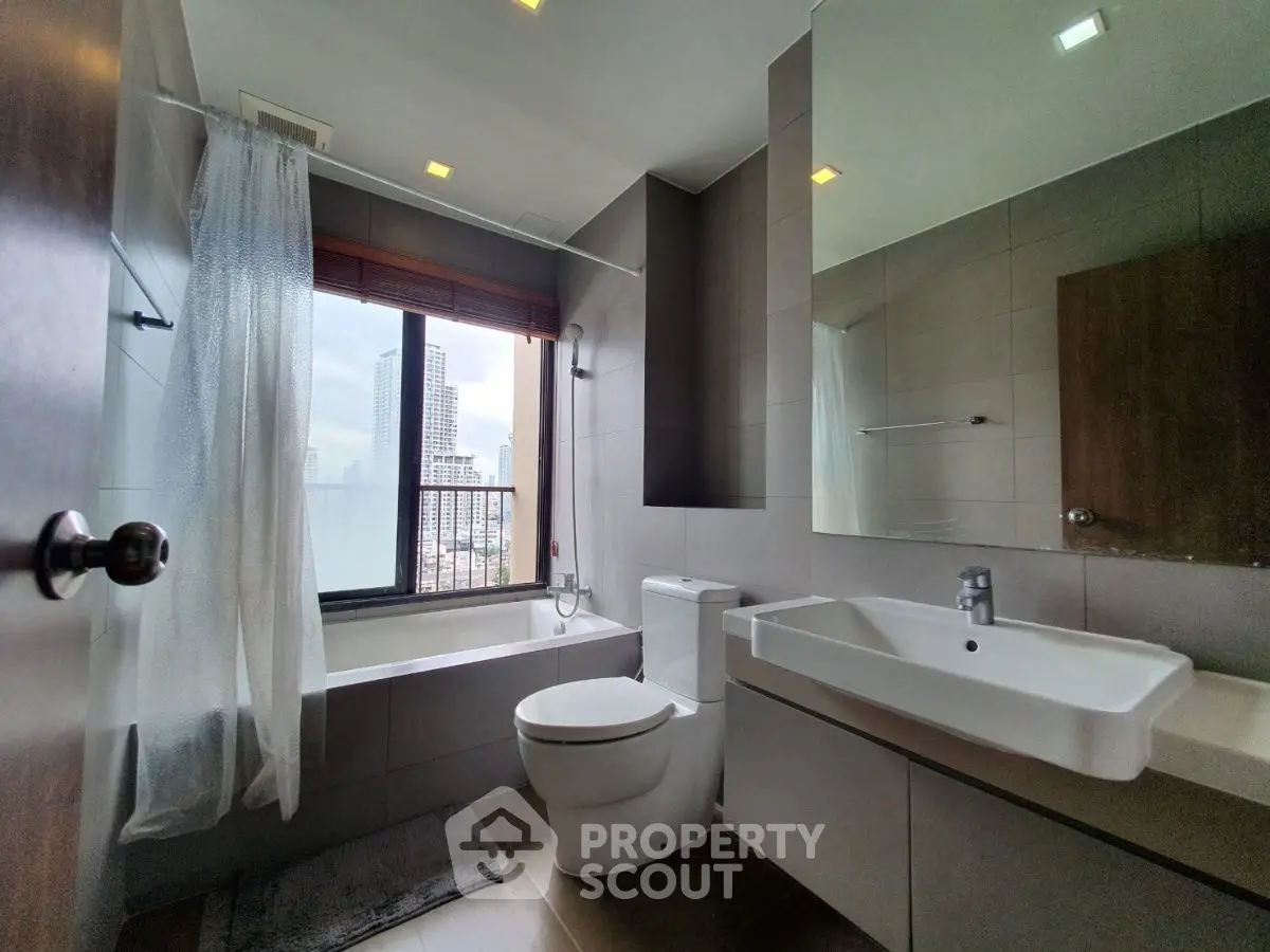 Modern bathroom with city view, featuring sleek fixtures and a bathtub, perfect for relaxation.