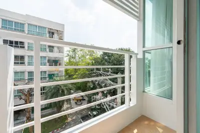 Modern balcony with glass railing and scenic view of lush greenery and contemporary building.