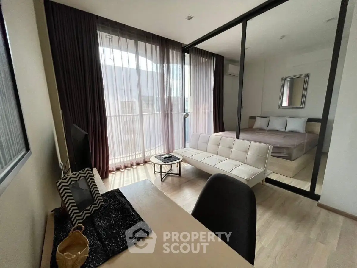 Modern studio apartment with glass partition, cozy living area, and stylish bedroom.