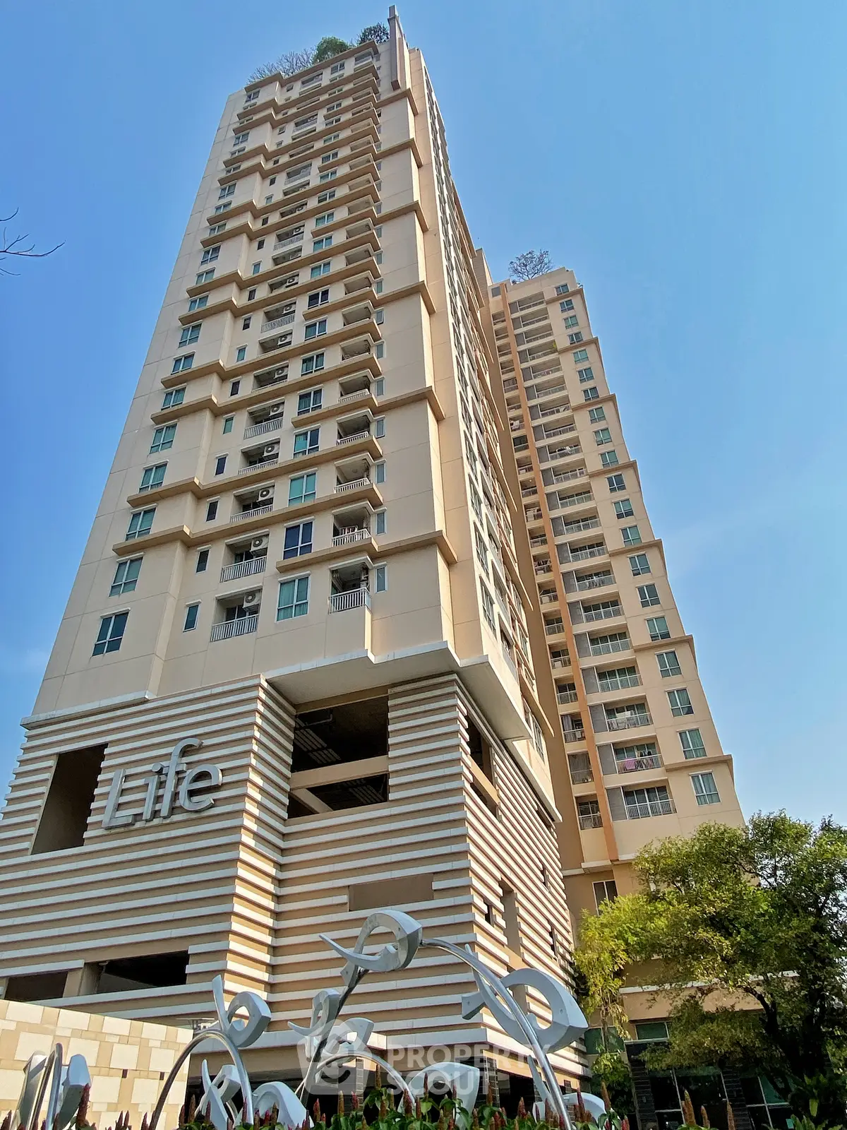 Modern high-rise residential building with unique architectural design and clear blue sky backdrop.