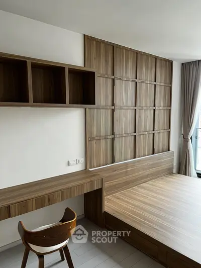 Modern bedroom with wooden accents and built-in desk, featuring large window with natural light.