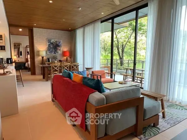 Spacious living room with modern decor and large windows overlooking greenery.