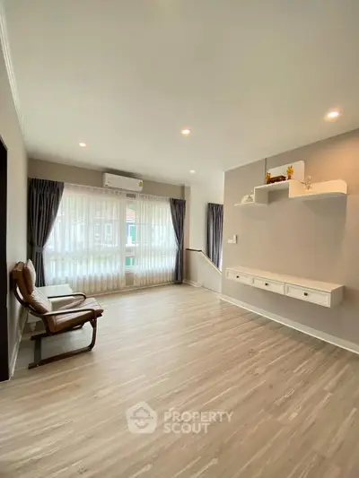 Spacious living room with modern decor and large window, perfect for relaxation.