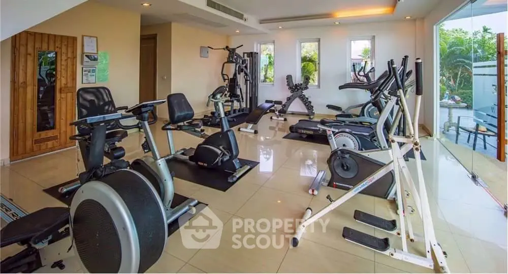 Spacious modern gym with state-of-the-art equipment and large windows offering garden views.