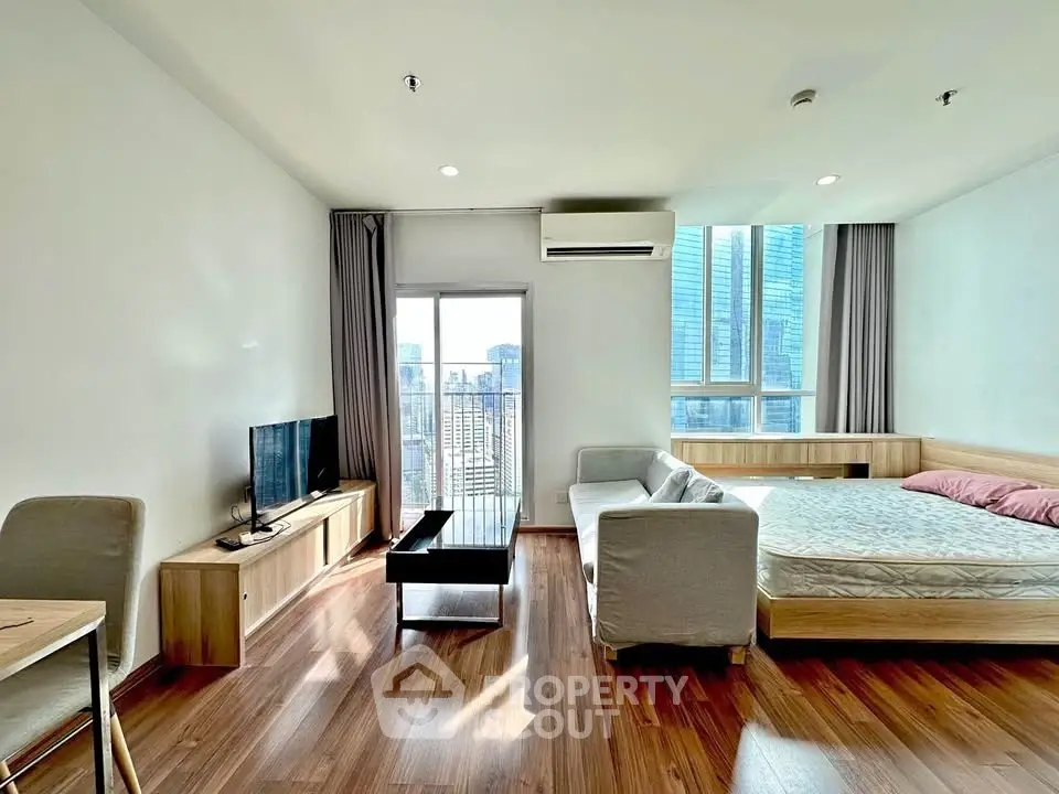 Modern studio apartment with city view, featuring sleek furniture and natural light.