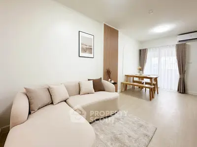 Modern living room with stylish beige sofa and dining area, featuring elegant decor and natural light.