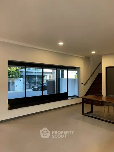 Spacious modern interior with large window and sleek staircase