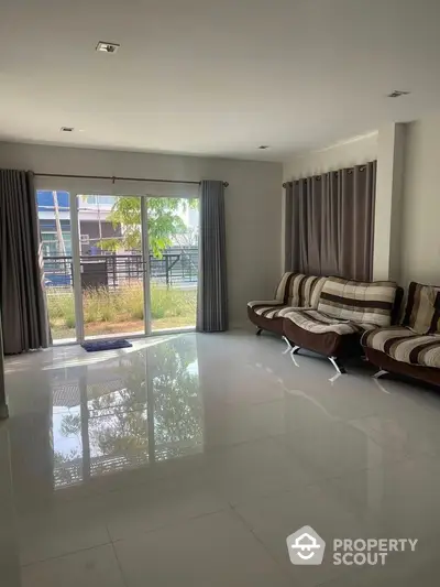 Spacious living room with modern furniture and large glass doors leading to garden view.