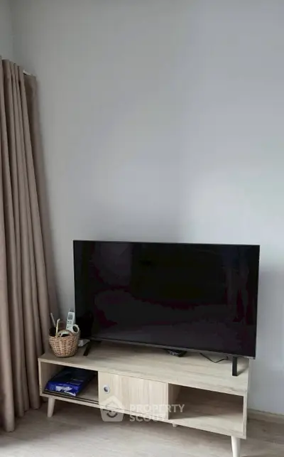 Modern living room with sleek TV and stylish wooden stand, perfect for entertainment.