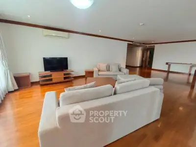 Spacious living room with wooden flooring and modern furniture in a luxurious apartment.