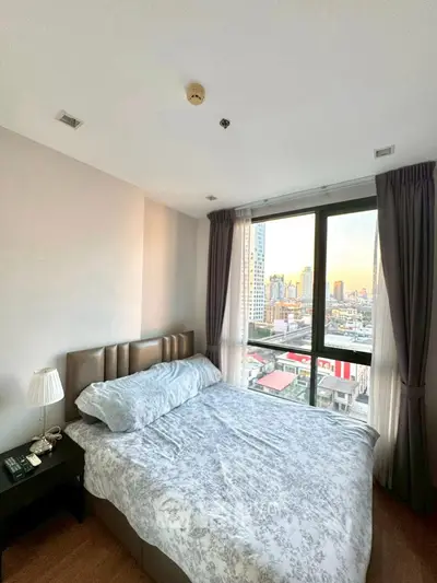 Cozy bedroom with city view, featuring a comfortable bed and large windows for natural light.