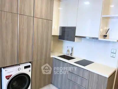 Modern kitchen with sleek cabinetry, built-in appliances, and washing machine in compact layout.