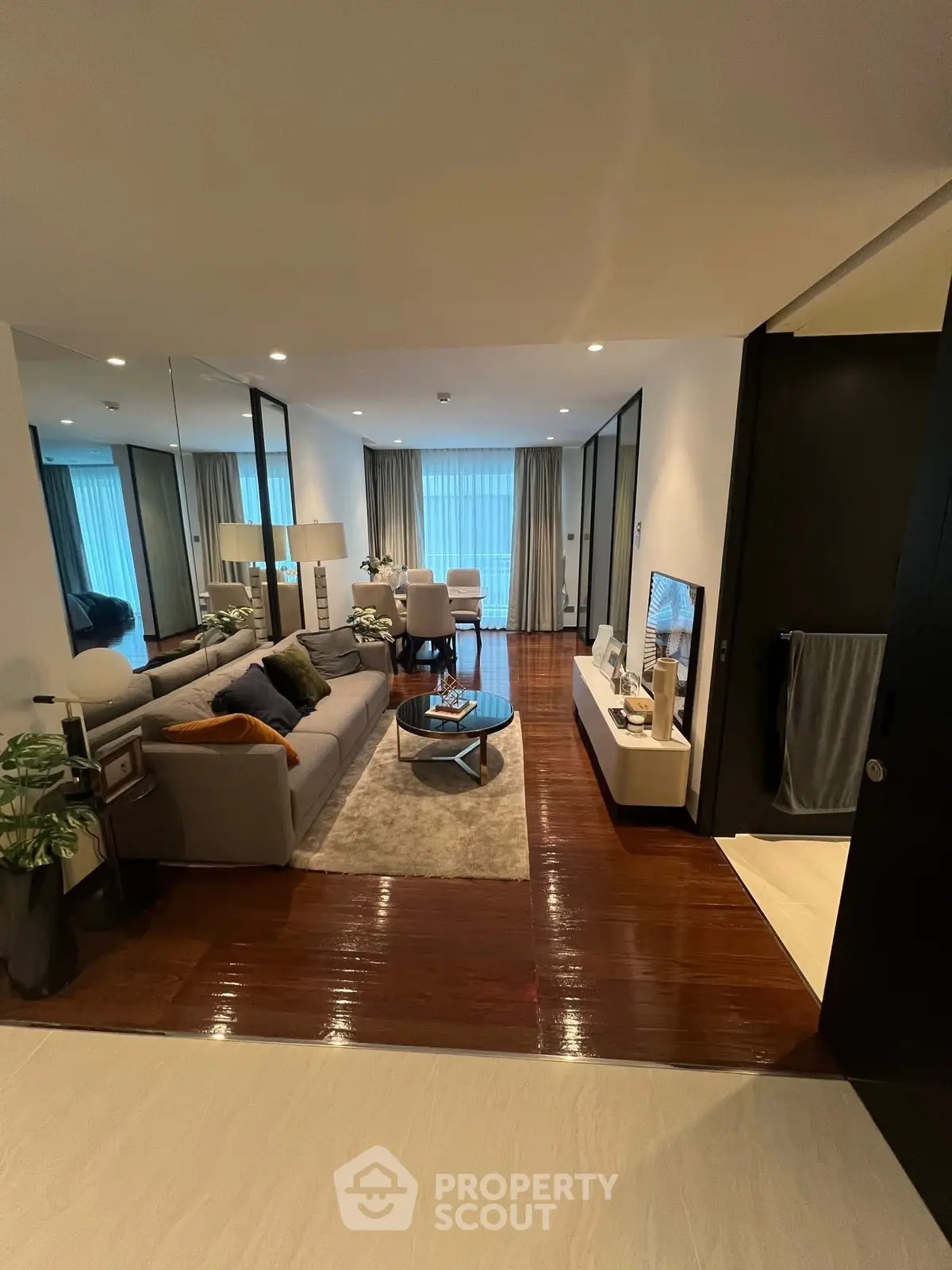 Modern living room with elegant decor and cozy seating area, featuring large windows and stylish furnishings.