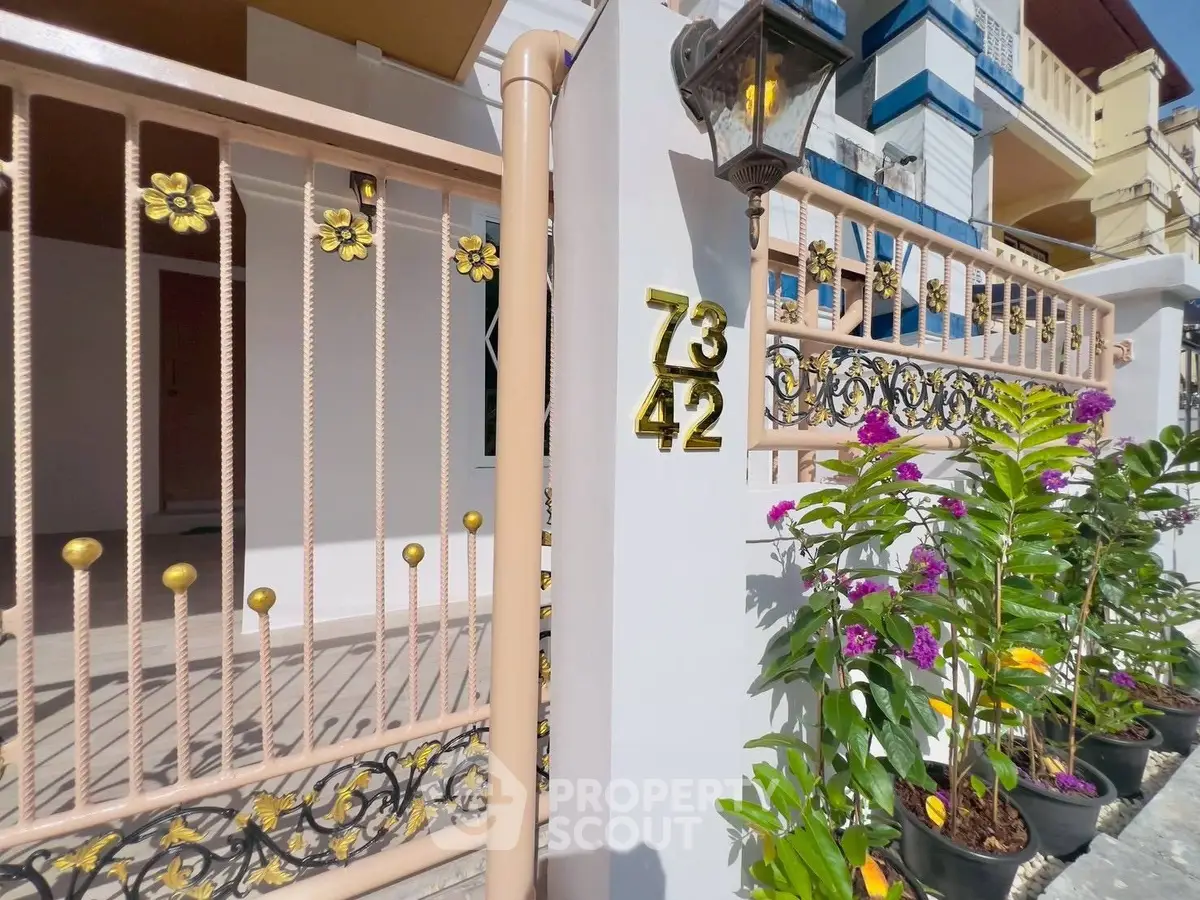 Charming house entrance with decorative gate and vibrant garden plants.