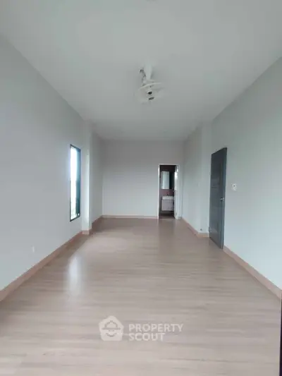 Spacious empty room with wooden flooring and ceiling fan, ideal for customization.