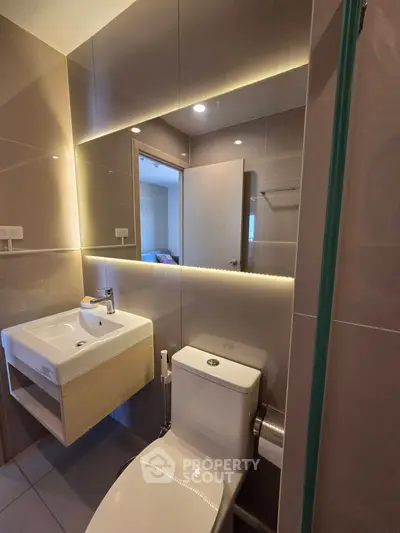 Modern bathroom with sleek design and ambient lighting, featuring a stylish sink and toilet.