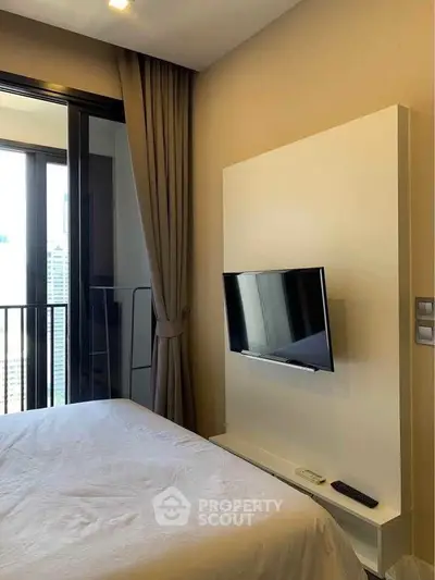 Modern bedroom with wall-mounted TV and balcony view in urban apartment