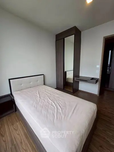 Modern minimalist bedroom with wooden flooring and sleek furniture design.