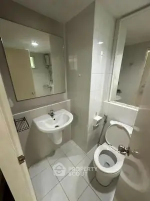 Compact bathroom with modern fixtures and large mirror, ideal for urban living.