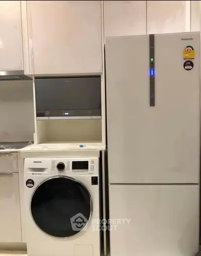 Modern kitchen with sleek appliances including washing machine and refrigerator.