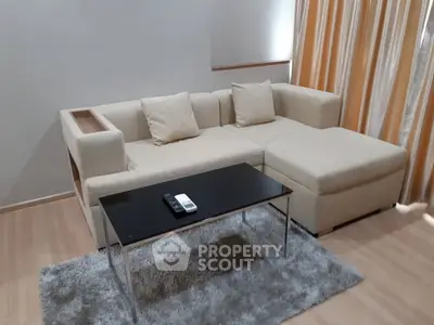 Modern living room with cozy beige sofa and sleek black coffee table on plush rug.