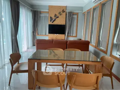 Spacious living room with modern dining set and cozy seating area, featuring large windows and stylish decor.