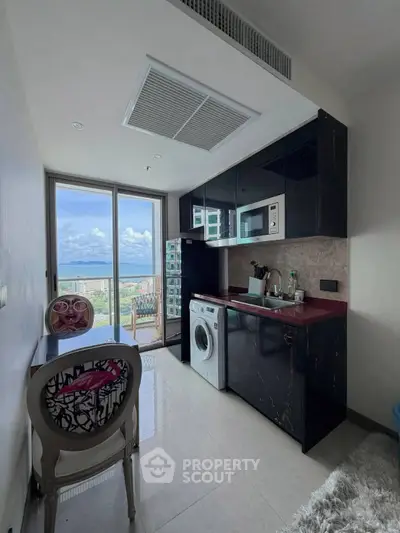 Modern kitchen with sleek black cabinets, washing machine, and balcony view in a stylish apartment.