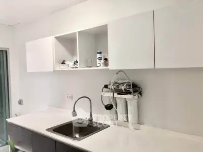 Modern kitchen with sleek white cabinets and built-in water filtration system.