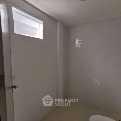 Minimalist bathroom with small window and tiled walls