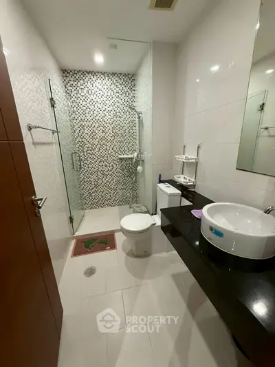 Modern bathroom with glass shower and sleek black countertop