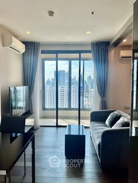 Modern living room with city view, featuring sleek furniture and large windows for natural light.