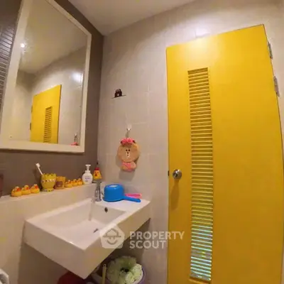 Charming bathroom with vibrant yellow door and modern sink, perfect for a cozy home.