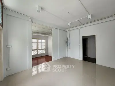 Spacious empty room with tiled flooring and large windows, ideal for customization.