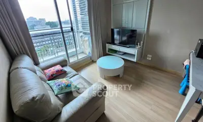 Cozy living room with balcony view, featuring a comfortable sofa and modern TV setup.