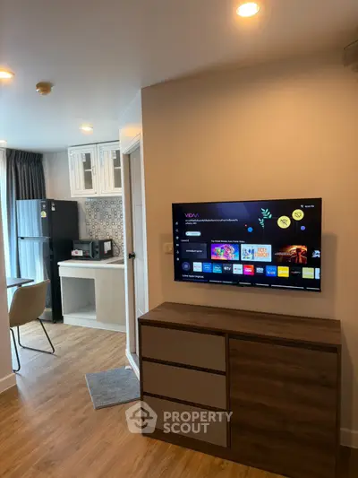 Modern living room with smart TV and stylish kitchen in open layout apartment.