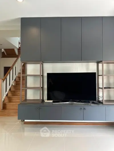 Modern living room with sleek TV unit and wooden staircase