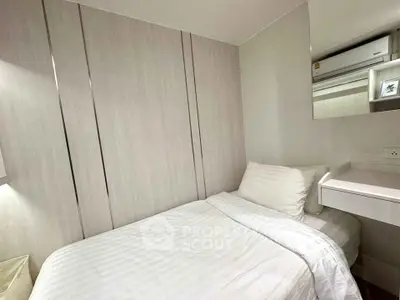 Cozy modern bedroom with white bedding and sleek design, featuring built-in storage and air conditioning.