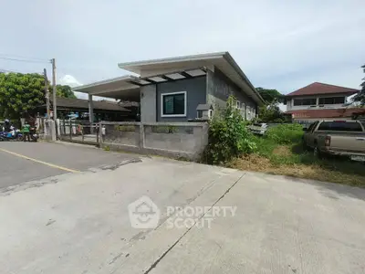Modern single-story house with spacious driveway and lush greenery in suburban neighborhood.