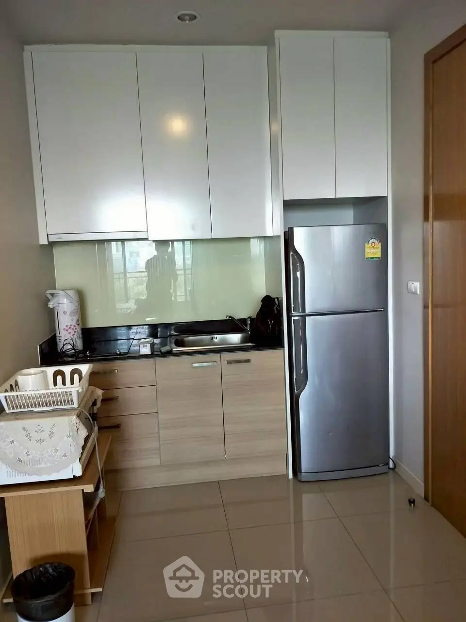 Modern kitchen with sleek cabinets and stainless steel fridge in compact layout.