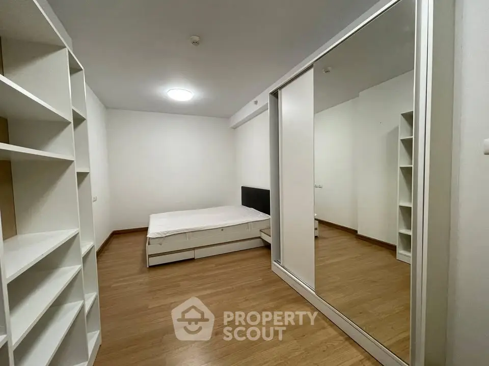 Spacious bedroom with wooden flooring and mirrored wardrobe