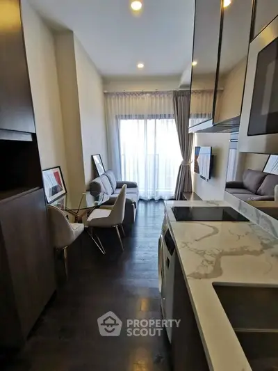 Modern apartment with open kitchen and cozy living area, featuring sleek furniture and large windows.
