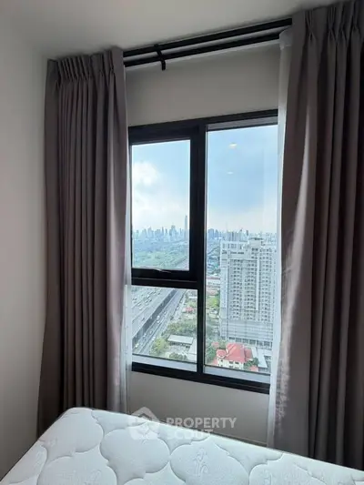 Stunning city view from a cozy bedroom window with elegant curtains and a comfortable mattress.