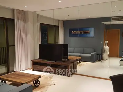 Modern living room with stylish decor and large mirror wall enhancing space.