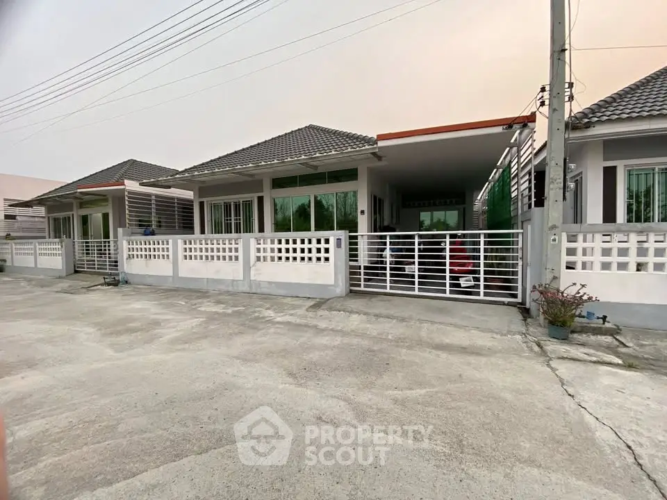 Charming single-story house with modern facade and gated driveway in a serene neighborhood.