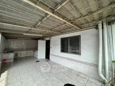 Spacious tiled outdoor area with covered ceiling and utility sink, ideal for versatile use.