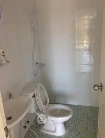 Compact bathroom with white tiles and basic fixtures, ideal for small spaces.