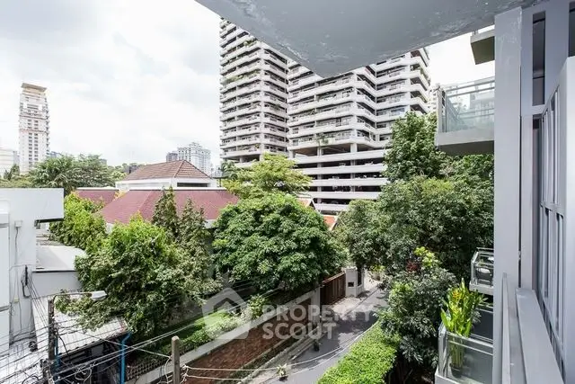 Stunning urban view from a modern balcony overlooking lush greenery and cityscape.