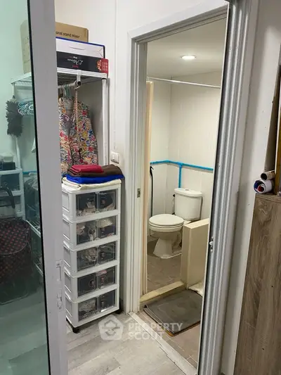 Compact bathroom with adjacent storage area in a cozy apartment setting.
