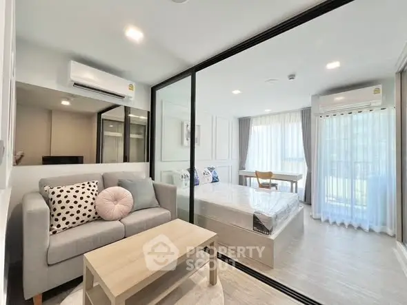 Modern studio apartment with glass partition, cozy living area, and bright natural light.