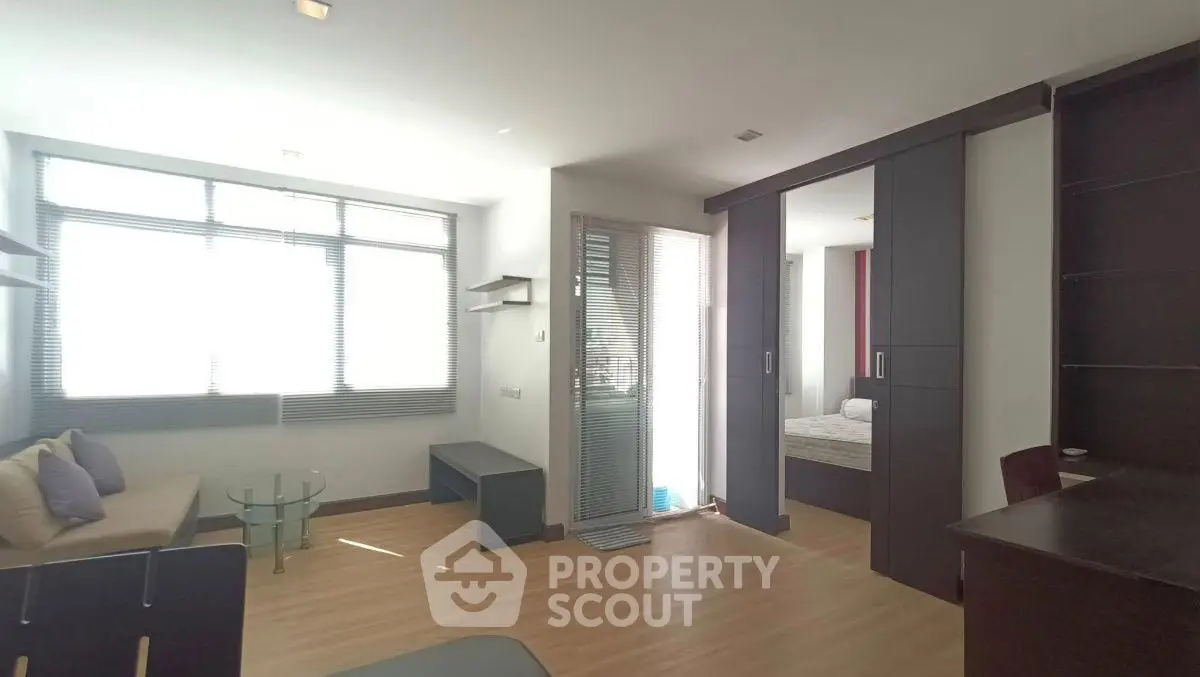 Modern apartment interior with open layout, featuring a cozy living area and bedroom separated by sliding doors.